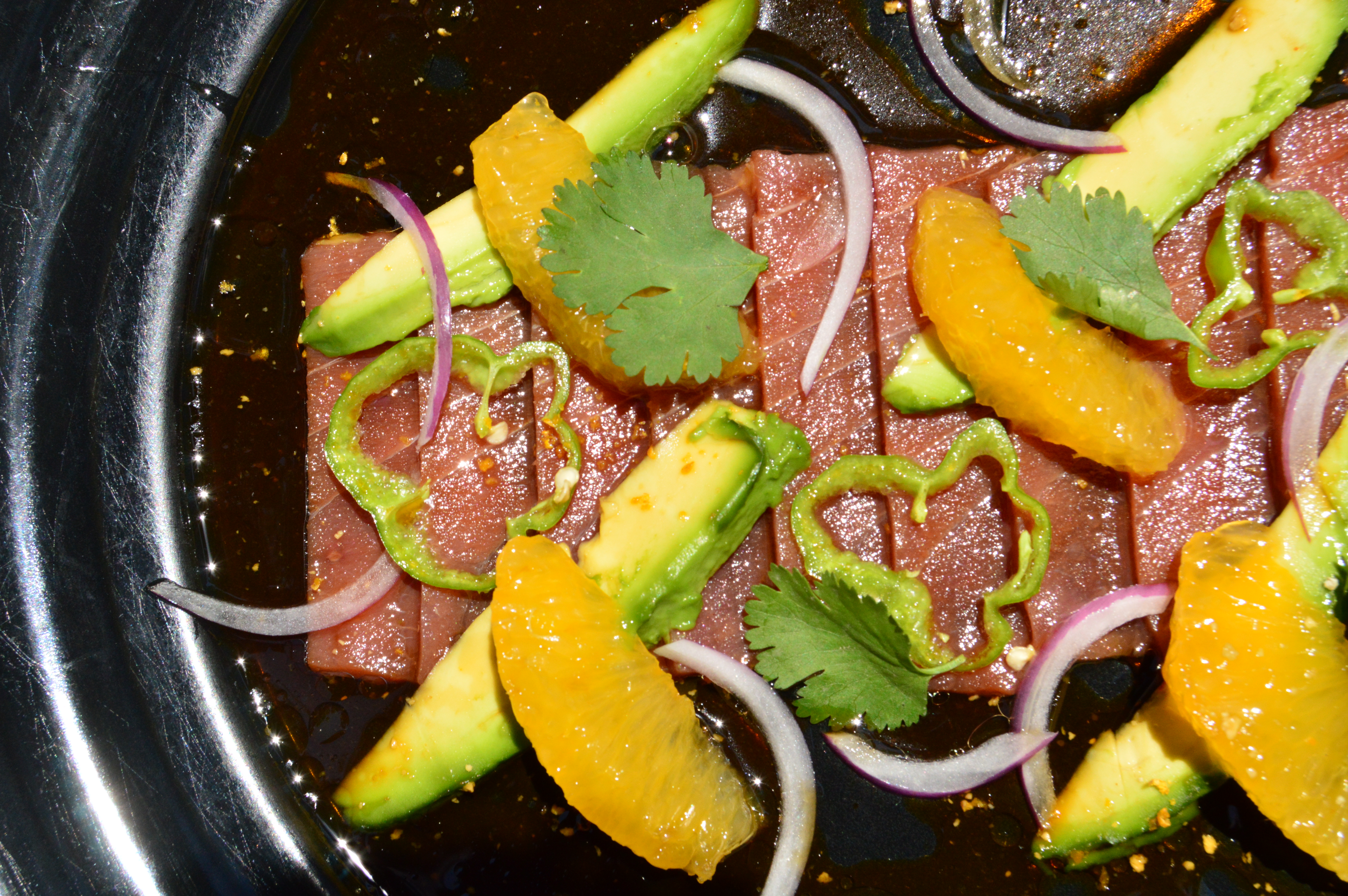 Tiradito de atún fresco con cebolla morada, aguacate, perejil y suprema de naranja en Baja Streetfood