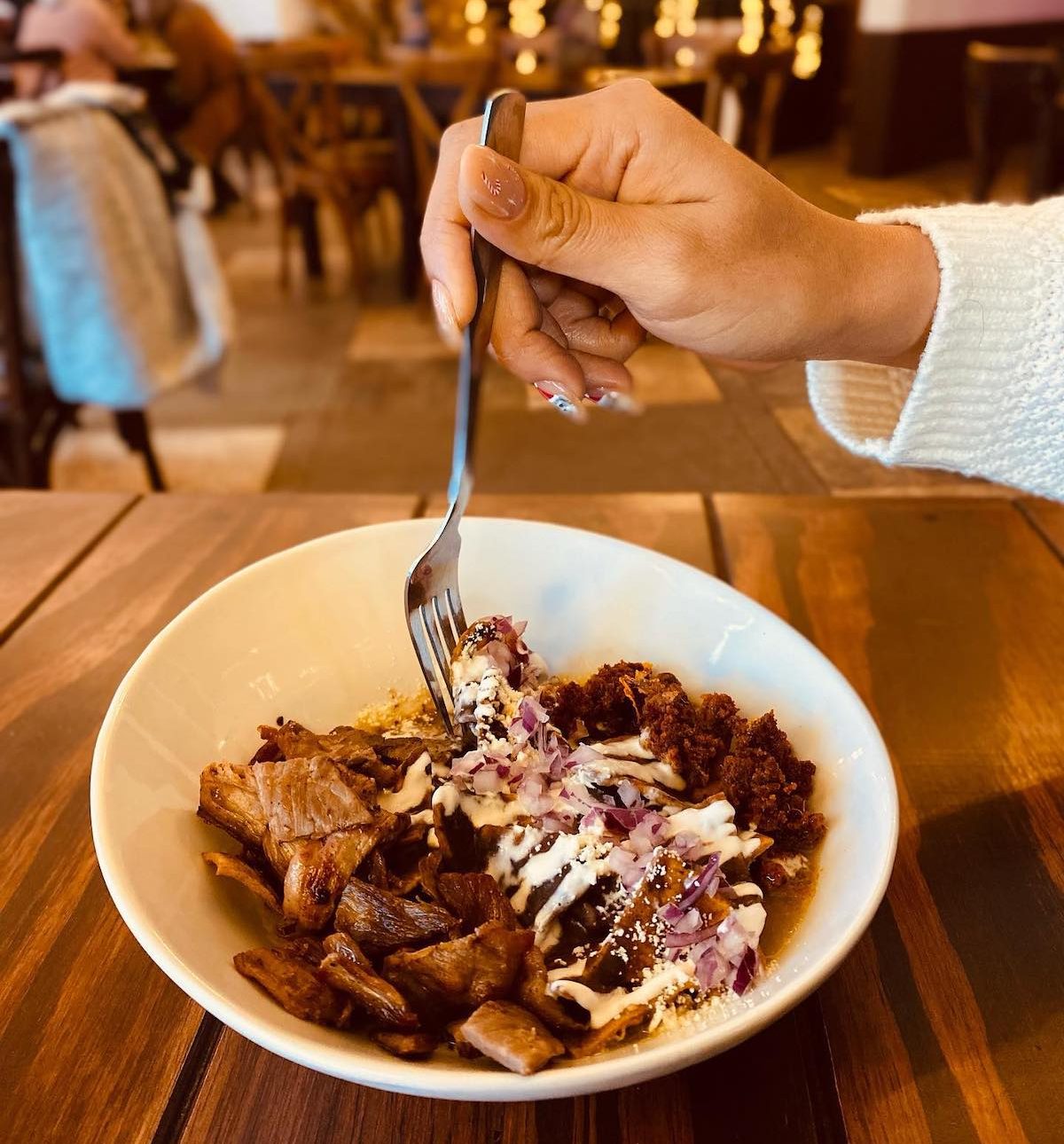 Mujer comiendo chilaquiles petroleros de frijoles