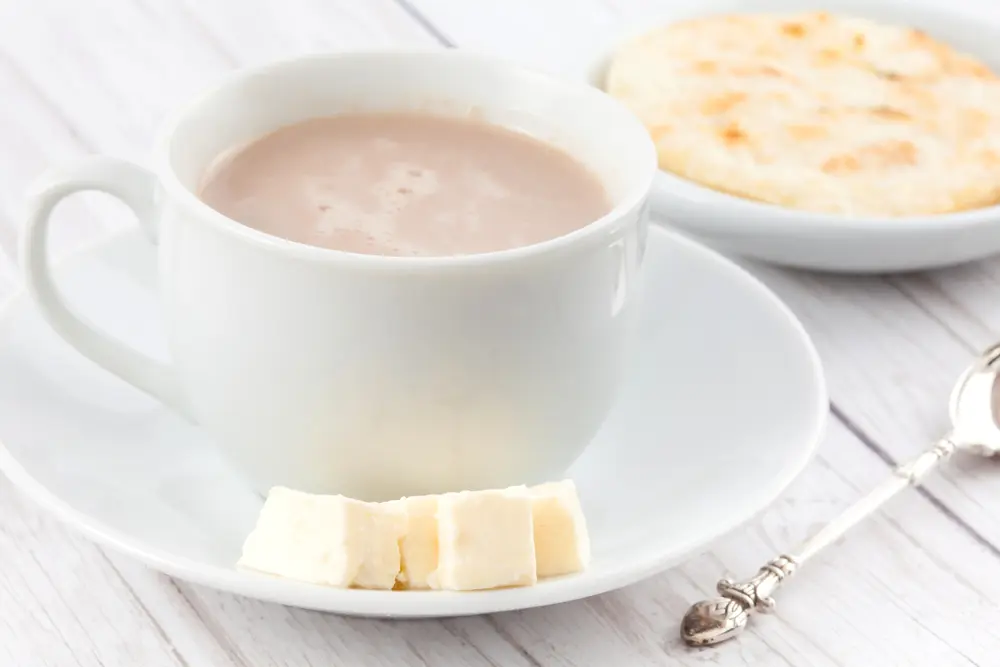 Taza de chocolate caliente con queso y una arepa, desayuno en colombia