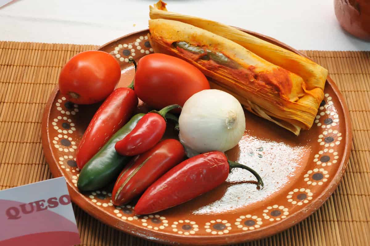 Los tamales rojos con rajas se preparan con tomate rojo o jitomate, rajas poblanas y queso fresco.