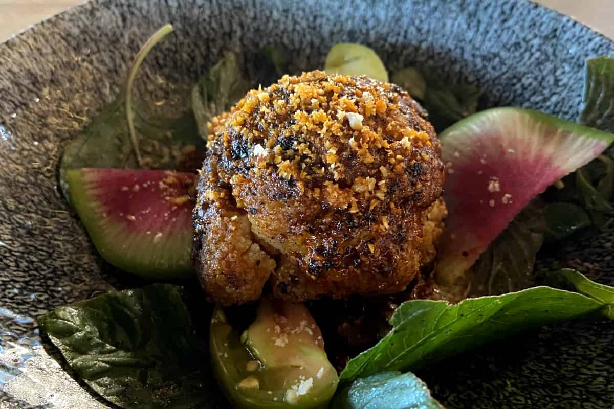 Coliflor asada con salsa macha de la casa acompañada con sikilpak de ajo, falso parmesano de nuez y brotes de temporada del menú del Chef Obed Reyes. / Foto: Animal Gourmet