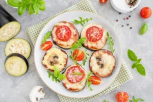 Prepara mini pizzas vegetales usando rebanadas de berenjena o calabacín como base, agrega salsa de tomate, queso bajo en grasa y vegetales variados como champiñones y pimientos. / Foto: iStock