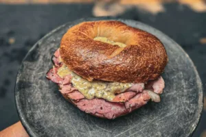 Salami ahumado, crema de espinacas con champiñones y queso gouda, mostaza de la casa y cebolla morada. / Foto: cortesía @valhalla_bagels